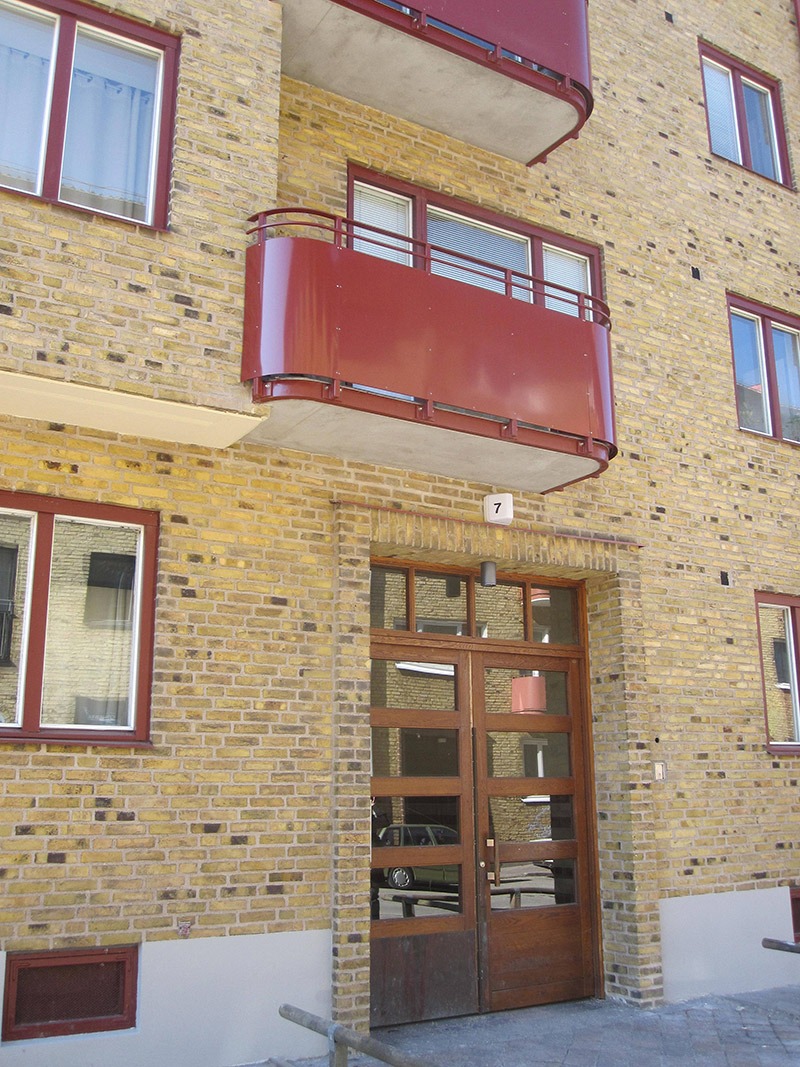 Den gula tegelfasaden med röda balkonger efter renovering