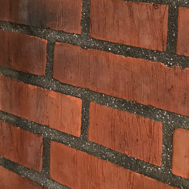 Svartgrå tegelfog med marmorkross i Brf Cederns röda tegelfasad.